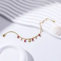 Close-up of gold-plated sun charm bracelet with pink beads and shell background - Sun Pendant Rose Red Beads Style