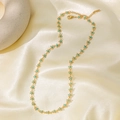 Detail view of gold titanium necklace with light blue floral charms on silk background - Small Blue Flower Necklace - Gold