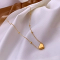 Détail d'un pendentif cœur doré sur une chaîne en acier titane perlée sur de la soie - Style Perle Cœur X1208 / Or