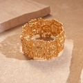 Dettaglio di un bracciale largo in oro opaco con rilievo floreale su fondo in pietra - Oro