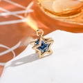 Macro shot of 14K gold star pendant with vibrant blue zircon stone and top ring - Star - Light Blue