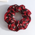 Close-up of red and black plaid plush scrunchie with festive white snowflake patterns - Red Snowflake Black Plaid
