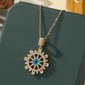 Détail du collier œil protecteur doré avec émail bleu et zircons sur un écrin vert - A34 - Or