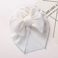 Detail of white baby beanie featuring waffle texture and large bow decoration - White