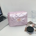 Lifestyle shot of a pale pink quilted makeup bag on a white desk with daily accessories - Purple