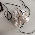Close-up of cream satin scrunchie featuring a long black ribbon bow on white background - Off White
