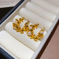 Dettaglio di orecchini a U dorati con perle su sfondo di velluto beige elegante - Stile cerchio / Oro