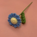 Handmade crochet rose with blue petals and yellow center on a pink background - Light Blue Camomile
