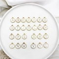Macro detail of 26 round white enamel and gold alloy alphabet charms in a white tray - Letter A / 2#White Letter
