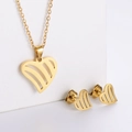 Close-up of golden hollow heart necklace and stud earrings set on white display stands - Striped Heart