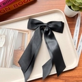 Close-up of a large black double-layered satin bow hairclip on a decorative tray - Black 06