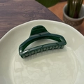 Detailed view of large dark green perfume bottle hair claw clip on a stylish cream tray - Bottle Green