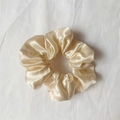 Elegant champagne gold satin scrunchie with silky luster on a white fabric background - Milk Yellow