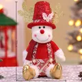 Plüsch Schneemann Puppe mit goldenem Geweih und rotem Paillettenhut in warmem Licht - Roter sitzender Elch