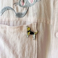 Détail d'une broche en émail chien Beagle sur une poche de chemise rose, texture métal - Style Foxhound