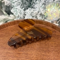 Close-up of amber tortoiseshell hair claw with gold France lettering on a wooden tray - American Coffee Tortoiseshell - Round Top 8-Teeth