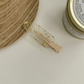 Dettaglio di un fermaglio per capelli trasparente con foglie d'oro e base in metallo - Foglia d'Oro Trasparente