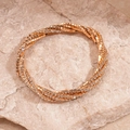Macrodetail van de gelaagde roségouden armband met sprankelende strassteentjes op steen - Goud