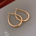 Dettaglio ravvicinato di orecchini a cerchio ovali dorati con design a goccia lucido - Oro
