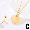 Détail d'un pendentif cœur à facettes sur une chaîne dorée avec de jolies fleurs séchées - Jaune