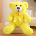Süßer hellgelber Teddybär Plüschtier mit gelber Schleife sitzend auf einem Schreibtisch - Gelb