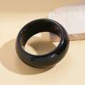 Close-up of a glossy black resin bangle on a neutral beige background with natural stone - Bangle - Black Round