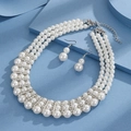Detailed view of the multi-layer pearl necklace and matching earrings on a blue surface - 3-Row Pearl Rhinestone Necklace Earring Set