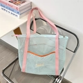 Detail of blue mesh beach tote bag with pink straps and orange pocket on chair - Light Blue