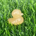Translucent yellow crystal duck figurine carved from natural stone on green grass - Golden Steatite