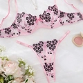Flat lay of pink lace lingerie set with black floral embroidery and rose decor - Pink