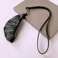 Close-up of minimalist black PU leather croissant pendant with zipper detail on a book - Black