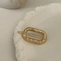 Detail of a golden hammered metal oval hair clip on a white decorative plate with dried flowers - Gold-Oval