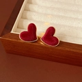 Dettaglio di orecchini a cuore in velluto rosso e metallo dorato su una scatola di legno - Stile Cuore / Rosso