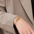 Elegante pulsera con hebilla de cinturón bañada en oro de 18 quilates sobre manga beige - Pulsera / Dorado