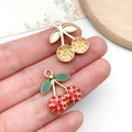 Detailed close-up of mini crystal cherry pendants for DIY jewelry making held by fingers - KC Gold Red Enamel Rhinestone Cherry (23424)