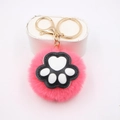 Close-up of pink faux fur pompom keychain with black and white cat paw detail - Cat Claw Gold Keychain / Watermelon red