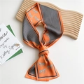 Orange skinny silk scarf featuring horse print and black wave patterns on wooden tray - Horse Ripple Patchwork Orange