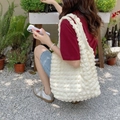 Detail of white popcorn textured tote bag worn by a model in a garden setting - Bubble Beige