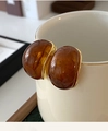 Detailansicht der ovalen Bernstein-Ohrstecker mit 18k Vergoldung am Rand einer Tasse - Gold & Kaffee Marmor Textur (Silberstift)