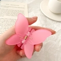 Pink matte butterfly hair claw clip for women shown in a hand with a lifestyle background - Pink Butterfly Claw Clip / Pink
