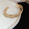 Macro-opname van een gouden gedraaide multi-strand armband op een wit bordje - Goud Gedraaide Gevlochten Stijl