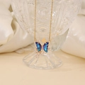 Detail of butterfly pendant necklace with purple crystals and gold chain on glass - Dark Blue