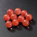 Polished natural strawberry quartz round beads set on a black textured background - Watermelon Red Stone