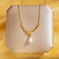 Collier en acier titane avec nœud et perle en goutte sur boîte à bijoux dorée - Perle de Nœud d'Or