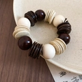Dettaglio ravvicinato del bracciale vintage con perline di legno e guscio di cocco - Stile color block bianco e caffè