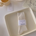 Creamy white ribbed mid-calf socks with striped texture on a cozy home tray - Beige