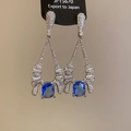 Dettaglio degli orecchini a goccia con zirconi blu e perno in argento su carta nera - Perno in argento - Argento - Blu