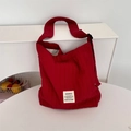 Macro-opname van rode geplooide canvas schoudertas met merklabel en verstelbare riem - Bordeauxrood