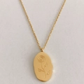 Detail of a golden oval pendant featuring a delicate rose flower engraving on a cable chain - June Rose