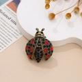 Macro de broche de mariquita en bronce retro con brillantes pedrería azul y roja - Mariquita Negra y Roja